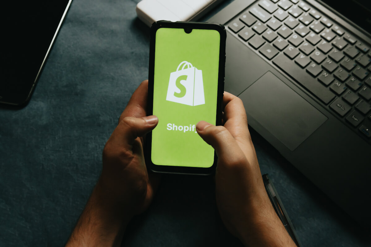 hands-holds-a-cell-phone-showing-the-shopify-logo.jpg